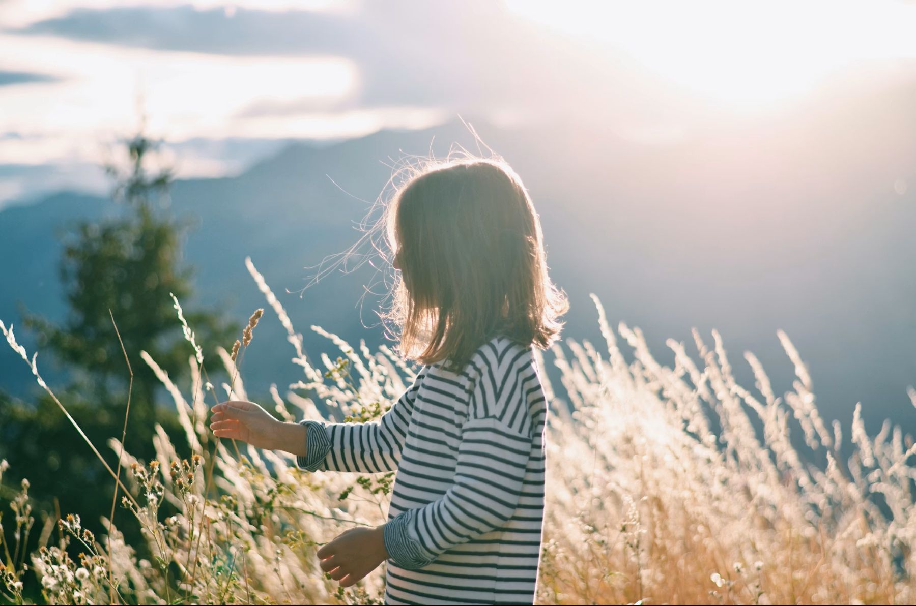 Mädchen steht bei Sonnenuntergang auf einem Berg - Angebot energetische Arbeit bei Kindern von Herzensenergetik Roswitha Piringer in Tamsweg im Salzburger Lungau